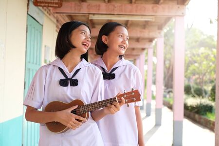 Asian young girls playing ukulele at school.