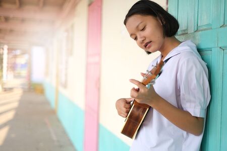 Asian young girl playing ukulele at school.の写真素材