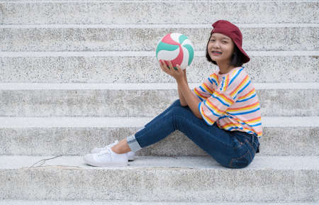 Asian young girl wear jean and colorful shirt hold volleyball with happy emotion.