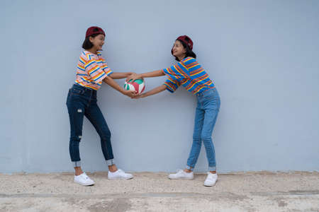 Asian young girl wear jean and colorful shirt hold volleyball with happy emotion.