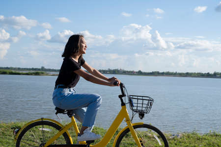 Happy young Asian girl riding a yellow bicycle at road in beautiful park .の写真素材