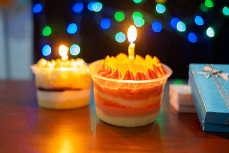 Delicious birthday cupcake with burning candle with bokeh.の写真素材