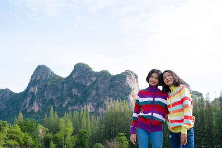 Two young girl have fun at beautiful landscape view of mountain and pine tree.