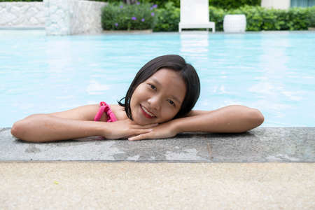 Young Asian girl having fun at swiming pool .