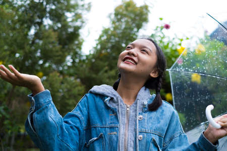 Happy young girl playing with rain in green garden.の写真素材