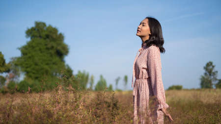 Young girl standing at field grass and blue sky.の写真素材