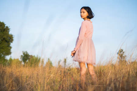 Young girl wear pink dress at the meadow and blue sky.の写真素材