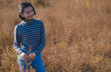 Happy young girl wear jean and sweater at brown field grass.の写真素材