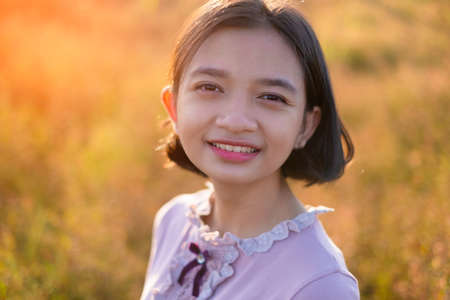 Portrait face of beautiful young girl at field grass in sunset time.の写真素材