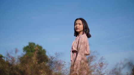 Happy young girl wear dress standing at the field grass.