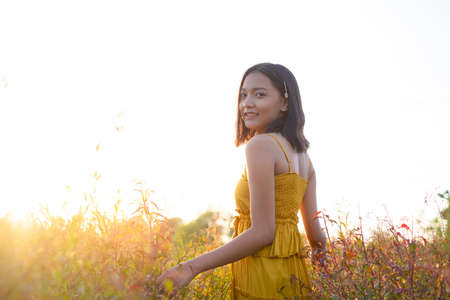 Young girl standing at brown field grass at sunset time.の写真素材