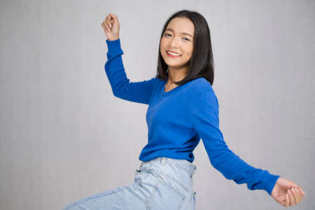Happy young girl wear blue sweater standing with gray background.の写真素材
