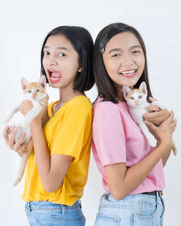 Two happy young girl wear pink and yellow shirt with two cat and white background.