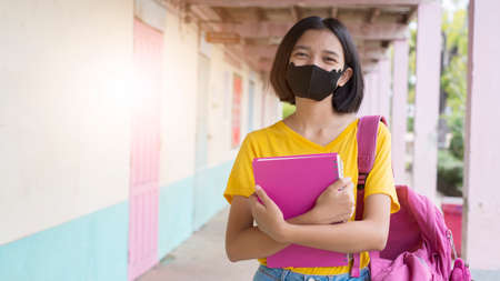 Student with face mask at school wear yellow shirt in white background.の写真素材