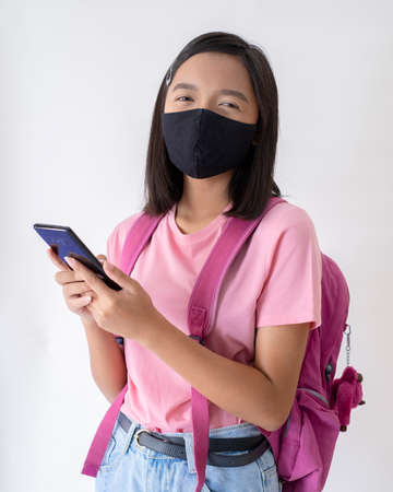 Student with face mask with smartphone wear pink shirt in white background.の写真素材