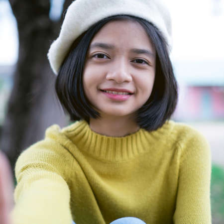 Portrait cute young girl smiling wear hat and yellow swater at park.の写真素材