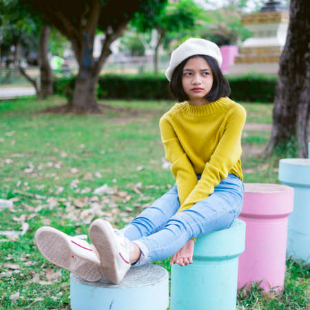 Asian young girl sitting at play ground wear yellow swater and jean.の写真素材