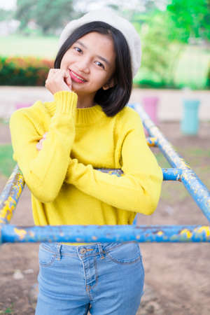 Happy young girl wear yellow sweater and jeans at playground.の写真素材
