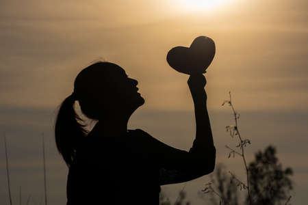 Silhouette picture girl hold heart with beautiful background.の写真素材