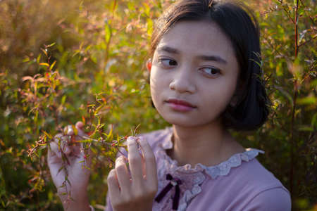 Young  girl has short hair at field grass, wear a beautiful pink dress.