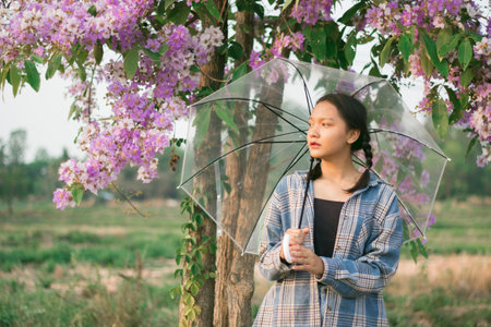 Asian young girl hold umbrella with purple flower.