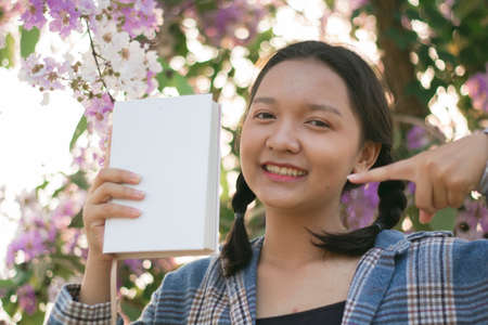 Beautiful young girl hold white book with purple flower.の写真素材