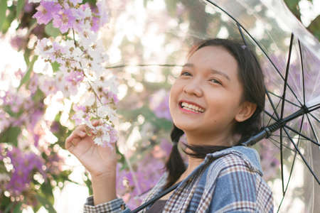 Asian young girl hold umbrella with purple flower.