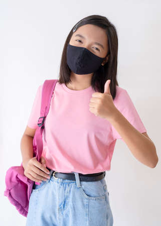 Young girl wear black mask ,pink shirt ,pink backpack on white background.の写真素材