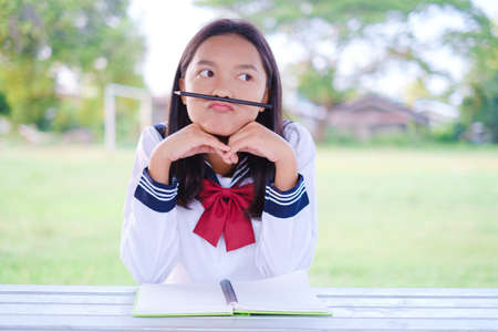 Happy student girl with book siting at out door at school, Asian girl.の写真素材