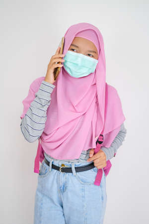 Muslim girls wear masks and use mobile phones on white background.の写真素材