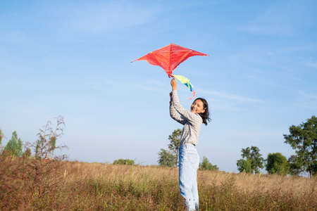 Happy young girl play kite at the meadow with blue sky.の写真素材