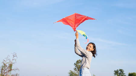 Happy young girl play kite at the meadow with blue sky.の写真素材