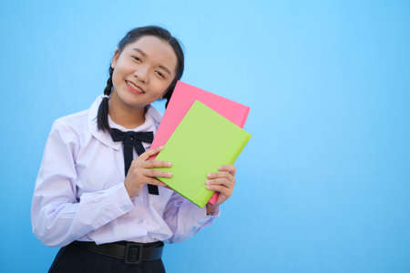 School girl hold book on blue background,Asian girl.の写真素材