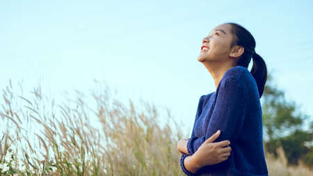 Beautiful young girl embrace her slfe at meadow and blue sky, Asian young girl.