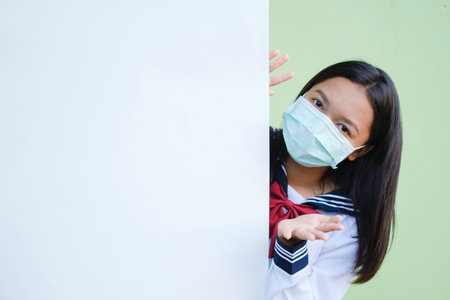 Smile young girl wear mask with bulletin board, green background,Asian girl.の写真素材