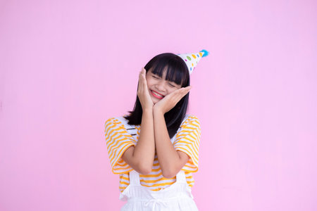 Happy young girl wear party hat on pink background,Asian girl.の写真素材