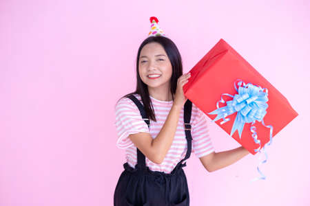 Happy young girl hold red box gift on pink background.の写真素材