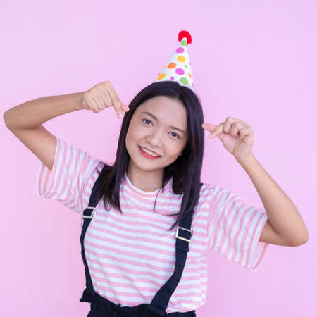 Happy young girl wear party hat on pink background,Asian girl.の写真素材