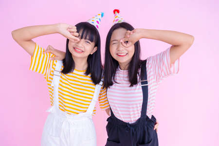 Happy girls wear party hat palying on pink background.の写真素材