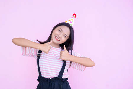 Happy young girl wear party hat on pink background,Asian girl.の写真素材