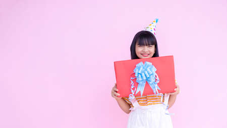 Happy young girl wear party hat on pink background,Asian girl.の写真素材