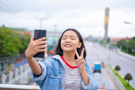 Portrait smile young girl use mobile phone on road background.の写真素材