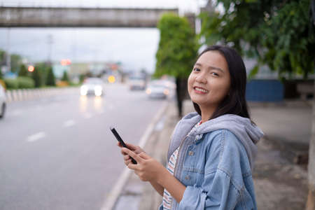 Portrait smile young girl use mobile phone on road background.の写真素材