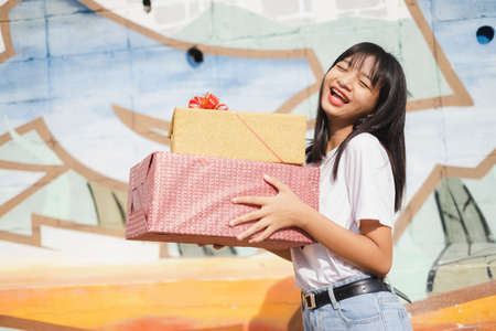Happy young girl holds the present box on colorful background. Asian young girl.の写真素材