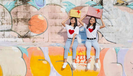 Two happy young girl with present box on colorful background.Asian girl.の写真素材