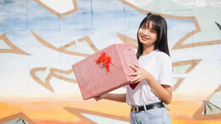 Happy young girl holds the present box on colorful background. Asian young girl.の写真素材