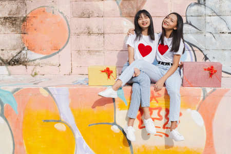 Two happy young girl with present box on colorful background.Asian girl.の写真素材