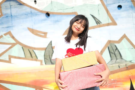 Happy young girl holds the present box on colorful background. Asian young girl.の写真素材