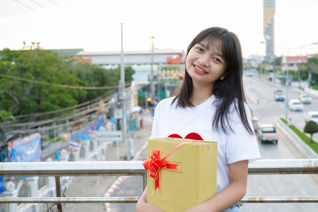 Happy young girl hold gift box on city view background.の写真素材