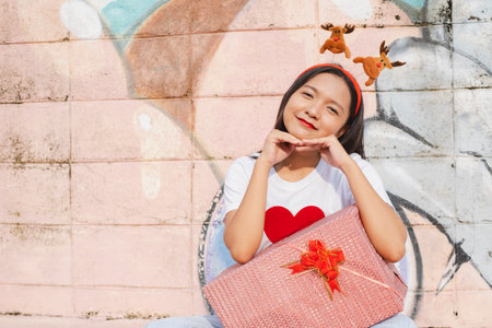 A beautiful girl wear Christmas hat hold present on colorful background.の写真素材